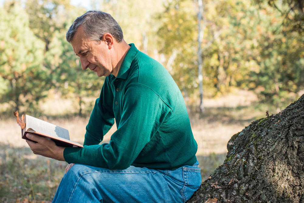 introverted retiree reading a book in the park