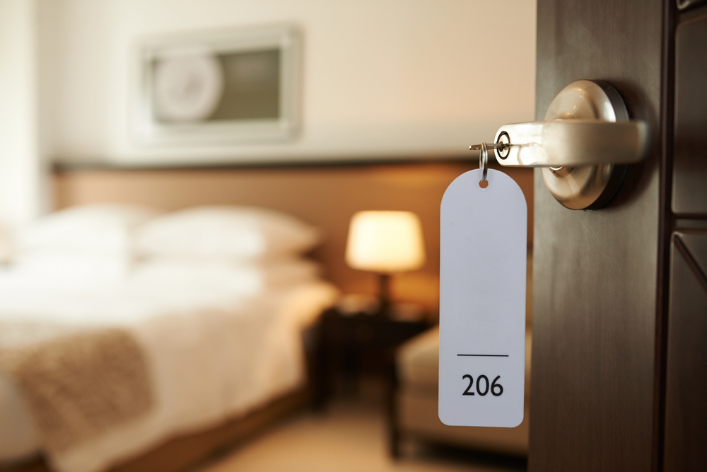 open door to hotel room with key in the lock